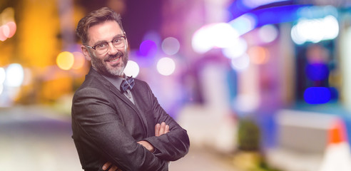 Fototapeta premium Middle age man, with beard and bow tie with crossed arms confident and happy with a big natural smile laughing at night club