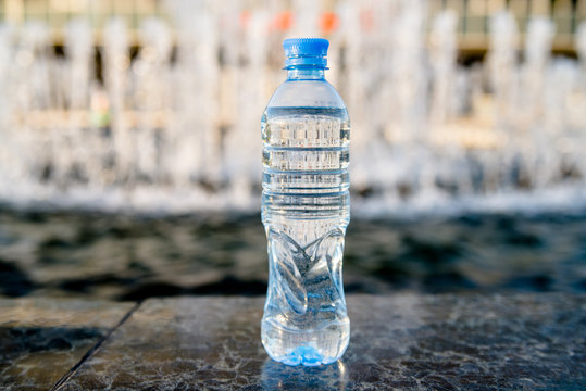 A bottle of drinking water stands on the background of the fountain