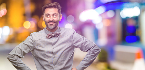 Middle age man, with beard and bow tie confident and happy with a big natural smile laughing at night club