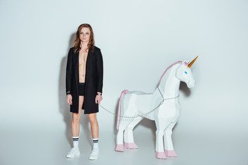 elegant man with big unicorn on chain, on grey © LIGHTFIELD STUDIOS