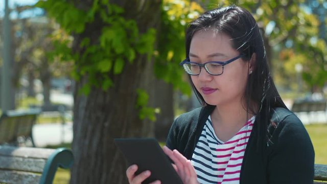 Asian Woman Using Kindle In Park 60fps