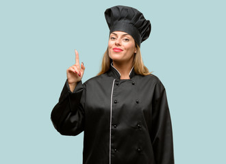 Young cook woman happy and surprised cheering expressing wow gesture pointing up