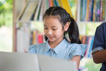 Students boy and girl in the library read books and ebook for education