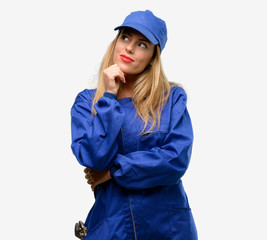 Young plumber woman thinking and looking up expressing doubt and wonder