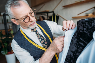 handsome tailor measuring shirt at sewing workshop