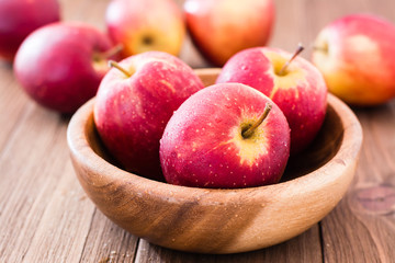 Red ripe apples in a wooden plate and on a wooden table