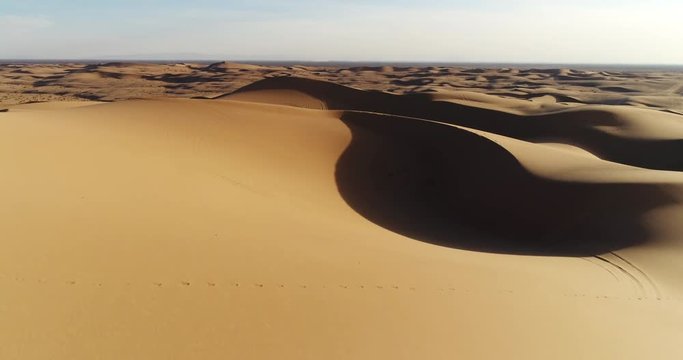 Aerial view flying over sand dunes in desert at sunset
