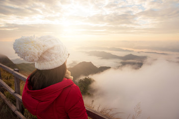 Fototapeta na wymiar Asian women standing and waiting to see the beautiful sunrise over the sea of mist at Phu Chi Dao mountain in Chiang Rai province of Thailand.