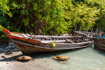 Broken traditional wooden boats in a shallow, tropical lagoon in Thailand