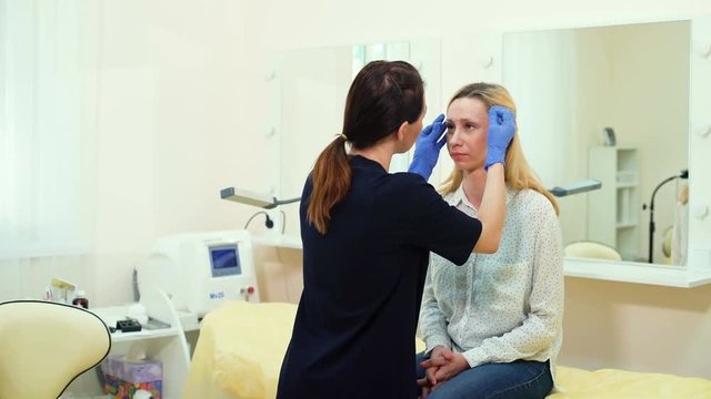Cosmetologist preparing woman for eyebrow permanent makeup procedure