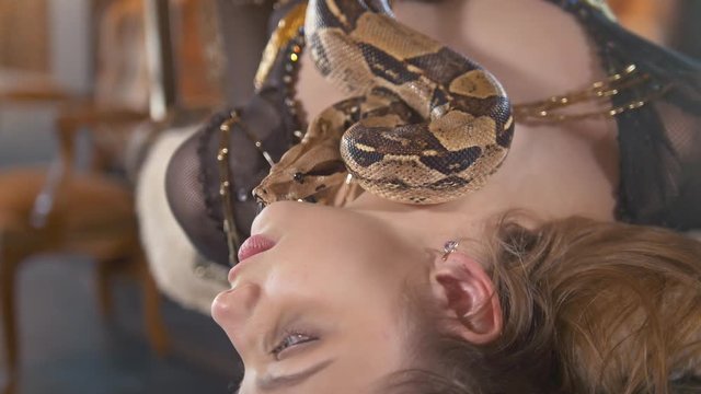 Portrait of young female dancer lying with a python