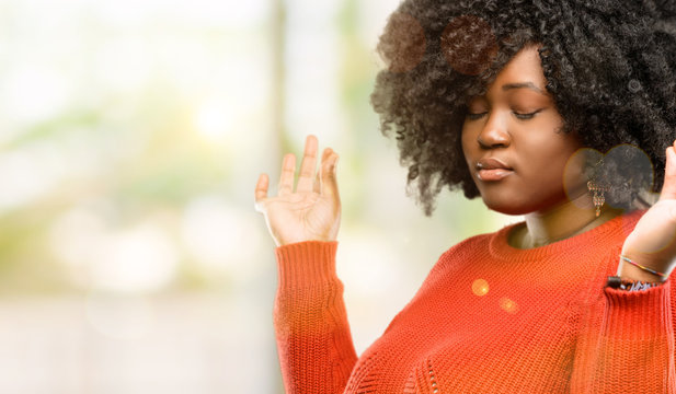 Beautiful african woman doing ok sign gesture with both hands expressing meditation and relaxation, outdoor