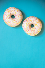 two glazed donuts isolated on blue background.freshly baked donuts , top view