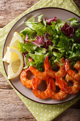 Shrimp fried in soy sauce and fresh salad close-up. Vertical top view