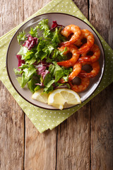 Delicious glazed shrimps with honey and soy sauce and fresh salad close-up. Vertical top view