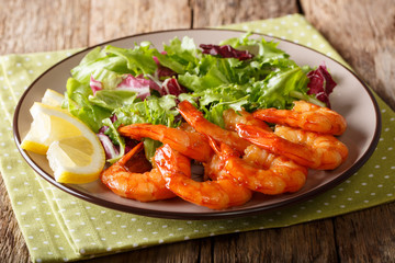 Fried prawns with honey and soy sauce and fresh leaf salad close-up on a plate. horizontal