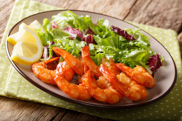Caramelized prawns with honey and soy sauce and fresh lettuce close-up on a plate. horizontal
