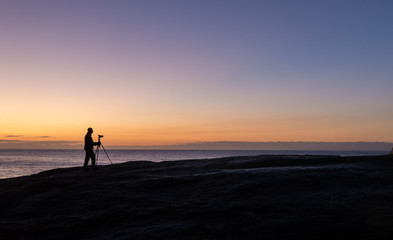 Fototapeta na wymiar Photographer at dawn at the Bow Hole, Tasmania