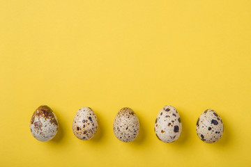 Beautiful spotted fresh quail eggs on a yellow paper background