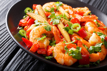 Shrimp with bell pepper, chili, garlic, corn cob and herbs close-up on a plate on the table. horizontal