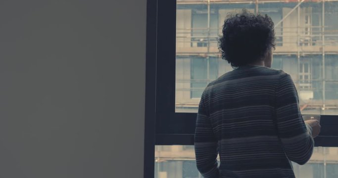 Young man drinking coffe by window