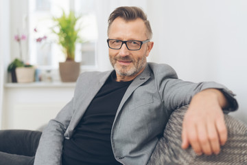 Mature man wearing grey jacket sitting on sofa