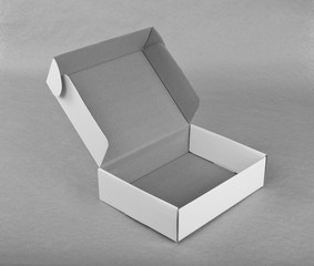 Opened white cardboard box for packaging on a gray background.