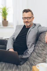 Mature man using laptop while sitting on sofa