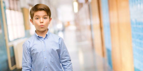 Fototapeta premium Handsome toddler child with green eyes expressing love, blows kiss at camera, flirting at school corridor