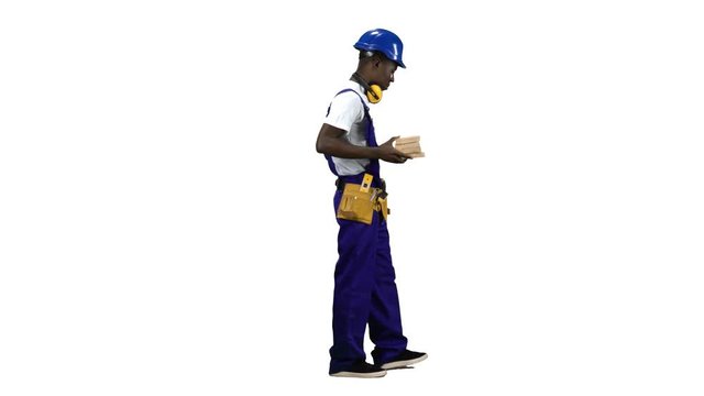 African American builder goes to work with wooden planks in his hands. Alpha channel. Side view