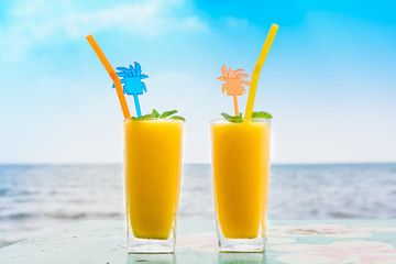 Two mango shake glasses on the tropical beach