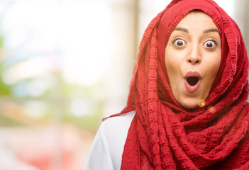 Young arab woman wearing hijab happy and surprised cheering expressing wow gesture