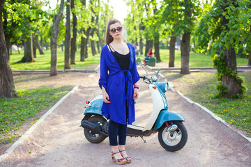 Young girl with a vintage dress sitting on a retro scooter
