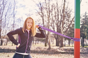 Beautiful sportswoman with smartphone exercising in park