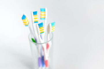 Group of plastic white toothbrushes in different colors in glass on white background. Free copy space.