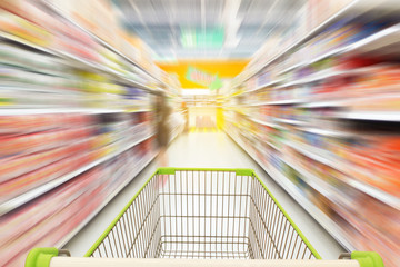 Supermarket aisle with empty green shopping cart