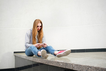 Redhead girl dressed in hoody, jeans and red sneakers