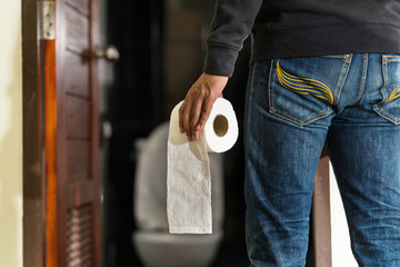 Fototapeta na wymiar Man holding tissue roll in toilet