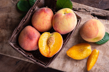 Ripe peaches in a basket on wooden, tropical fruit, top view