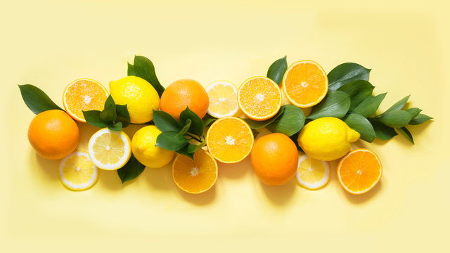 Summer set of tropical fruits, lemon, orange and green leaves on yellow. Banner.