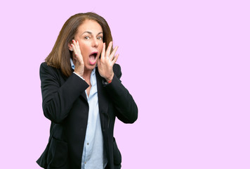 Middle age business woman stressful keeping hands on head, terrified in panic, shouting