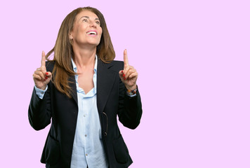 Middle age business woman happy and surprised cheering pointing up