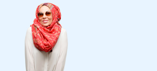 Middle age muslim arab woman wearing hijab thinking and looking up expressing doubt and wonder isolated blue background