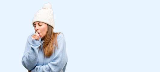Middle age woman wearing wool winter cap sick and coughing, suffering asthma or bronchitis, medicine concept isolated blue background