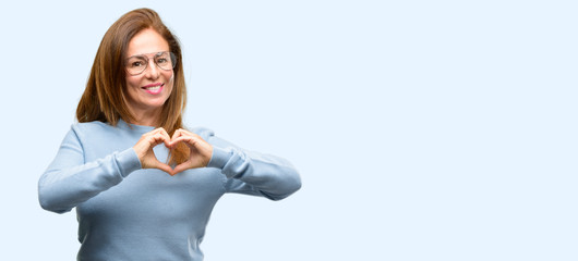 Middle age woman wearing wool sweater and cool glasses happy showing love with hands in heart shape expressing healthy and marriage symbol isolated blue background