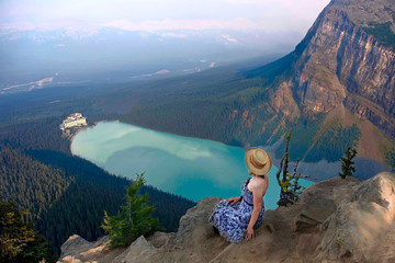 Obraz premium Woman sitting above Lake Louise with beautiful view of Fairmont Chateau hotel. Banff National Park. Canadian Rockies. Alberta. Canada.