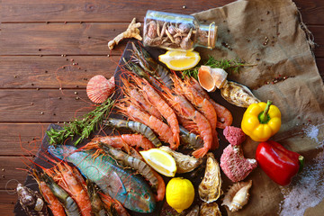 Royal and tiger shrimps, oysters, fish and ingredients for cooking. Mediterranean sea restaurant cuisine background.