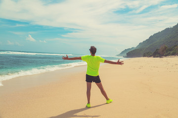 Man celebrating success after good training / exercise on a sandy ocean beach.