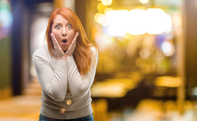 Fototapeta premium Beautiful young redhead woman happy and surprised cheering expressing wow gesture at night