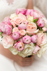 a wedding bouquet of roses and peonies in the hands of the bride. close-up. On a blurred background